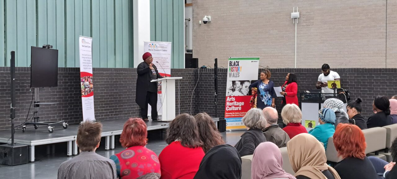Conference speaker addressing attendees of Race Council Cymru's Black Lives Matter event Codi Cymru